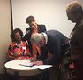 Director Sheldon signing the document May 6, with Jataun Rollins, Claudia Mosier and Jane Kelly (right).